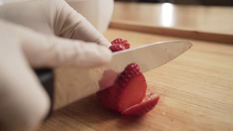 Chef-wearing-gloves-cutting-strawberry-meticulously,-close-up-low-angle
