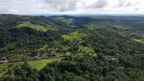 Aerial-view-moving-forward-shot,-houses-in-the-foothills-of-La-Tigra-Rain-Forest-in-Costa-Rica,-bright-blue-sky-in-the-background