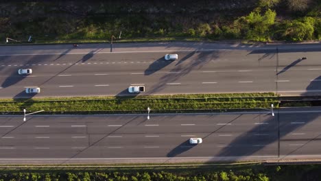 Aerial:-Busy-Multi-Lane-Highway-surrounded-by-green-Vegetation-on-roadside---Beautiful-weather-with-sunlight---Top-down-view
