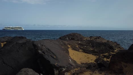 Bonita-Escena-De-Rocas-En-La-Costa-De-España-En-Tenerife-Con-Un-Yate-En-El-Fondo-Tiro-Con-Drones-En-4k-Mar-Junto-Al-Mar-Océano