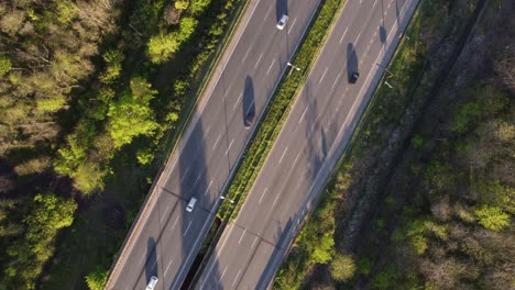 Aerial-top-down-over-Busy-Highway-with-traffic-on-asphalt-roadside-surrounded-by-rural-landscape-in-the-evening