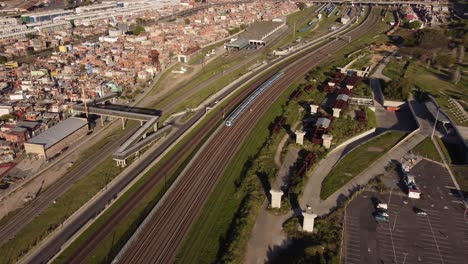Aerial-shot-of-train-arriving-commuter-train-station-beside-cityscape-of-Buenos-Aires-during-sunset---Panorama-view