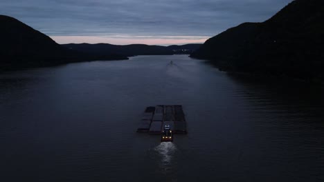 A-barge-pushing-large-shipping-containers-up-the-Hudson-River-in-New-York's-hudson-valley-just-after-sunset
