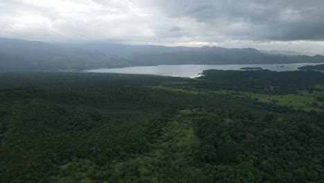 Aerial-view-tilting-up-shot,-Scenic-view-of-lake-in-the-La-Tigra-Rainforest-in-Costa-Rica,-cloudy-skies-in-the-background