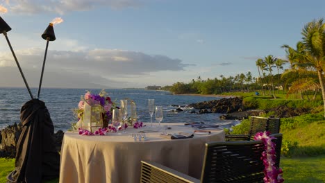 Romantic-table-for-two-overlooking-the-sea-and-sunset,-Maui-Hawaii---pan-left-and-slow-motion