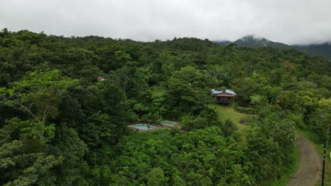 Aerial-view-Ascending-shot,-Scenic-view-of-the-house-with-a-Swimming-pool-in-the-La-Tigra-Rain-Forest-in-Costa-Rica,-cloudy-sky-in-the-background