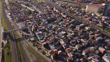 Aerial-flyover-poor-slums-neighborhood-surrounded-by-rail-tracks-and-highway-road-in-Buneos-Aires