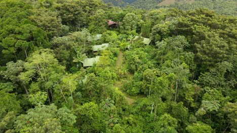 Aerial-view-moving-away-shot,-houses-in-the-middle-of-the-La-Tigra-Rain-Forest-In-Costa-Rica,-Scenic-view-forest-on-a-bright-sunny-day