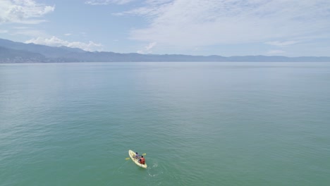 Dos-Personas-Remando-Un-Kayak-En-La-Playa
