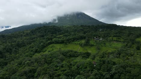 Aerial-view-moving-right-shot,-Rain-forest-in-Costa-Rica,-Scenic-view-of-Arena-Volcano-covered-in-clouds-in-the-background