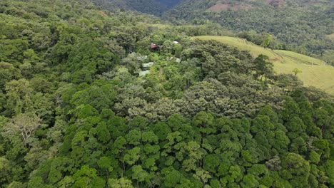 Aerial-view-moving-forward,-descending-shot,-approaching-house-in-the-middle-of-hills-of-La-Tigra-Rain-Forest-in-Costa-Rica