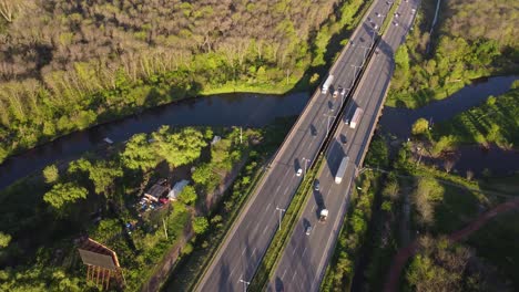 Orbit-shot-taken-of-traffic-movement-on-Pilar-Highway-in-Buenos-Aires,-Argentina-surrounded-by-plush-green-vegetation-and-going-over-a-creek