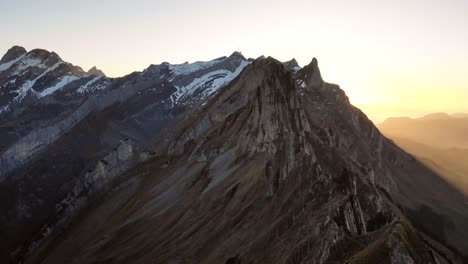Aerial-flyover-over-Schaefler-in-Appenzell,-Switzerland-at-sunset-above-a-hiker-on-the-ridge