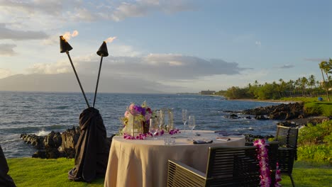 Romantic-table-for-two-overlooking-the-sea-and-sunset,-Maui-Hawaii---pull-back-and-slow-motion