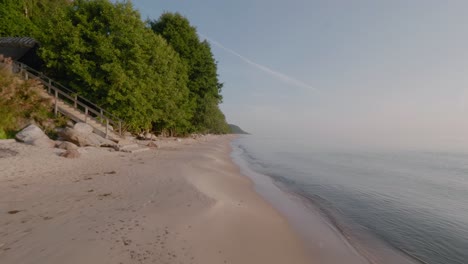 Knäbäckshusen-Beach-In-Österlen-With-Staircase-and-Cottage-By-The-Beech-Trees-in-The-Summer-Morning,-Wide-Shot-Tracking-Forward