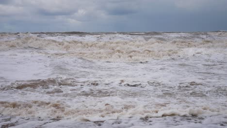Harsh-stormy-rolling-coastal-threatening-ocean-waves-foam-blowing-in-rough-windy-weather