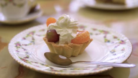 Biscuit-fruit-with-cream-on-top-as-a-dessert-to-a-coffe-break-served-on-old-fashioned-plate-with-a-spoon-slow-motion