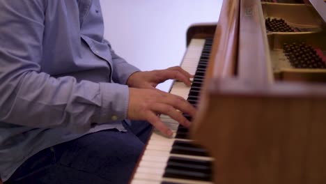 Una-Foto-Reveladora-De-Un-Pianista-Caucásico-Tocando-Un-Piano-Vintage-Con-Un-Fondo-Blanco-A-Cámara-Lenta