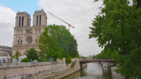 Reconstruction-Of-The-Iconic-Notre-Dame-de-Paris-Cathedral-In-Paris,-France-With-View-Of-Pont-au-Double-Over-The-Seine-River