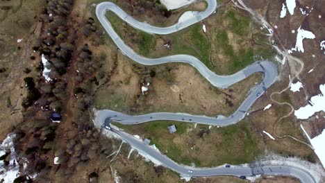 Top-down-view-of-a-curved-alpine-road-on-which-vehicles-are-passing-through-in-the-Italian-Dolomites