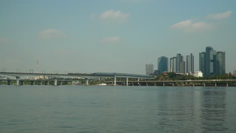 Two-Subway-Railway-Trains-moving-in-different-directions-on-Dangsan-Railroad-Bridge-over-Han-River,-Traffic-on-Gangbyeonbuk-ro-Expressway,-SEAH-Tower,-KB-Insurance-towers,-Mecenatpolis,-Seoul-Hapjeong