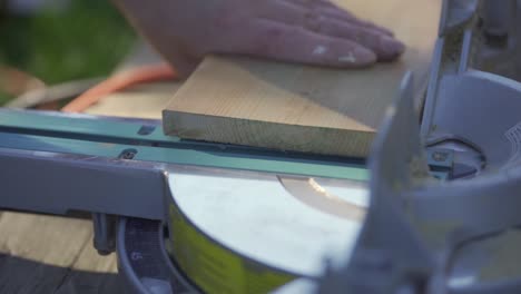 Man's-hands-separating-sawed-off-wooden-piece-from-mitre-saw