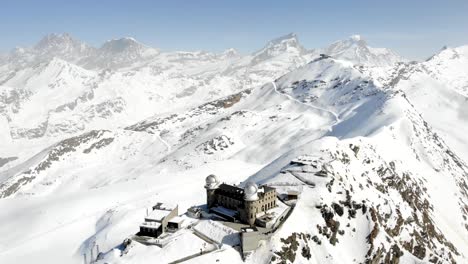 Aerial-flyover-with-a-full-rotation-around-winter-Gornergrat-with-views-of-Matterhorn,-Gornergrat-train-station-and-hotel,-Gorner-glacier,-Monte-Rosa