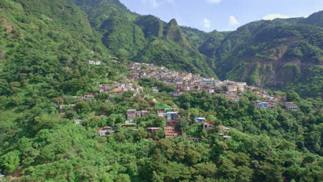 Drone-footage-of-volcanic-mountainside-indigenous-town-Santa-Cruz-La-Laguna,-Guatemala-in-Lake-Atitlan-in-Central-America-highlands-surrounded-by-lush-rainforest