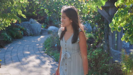 Attractive-young-Asian-woman-walking-through-a-beautiful-garden-path