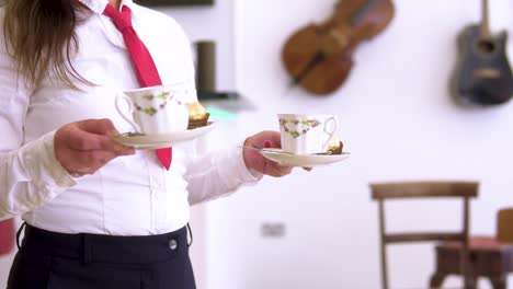 Kellnerin-In-Eleganter-Uniform-Mit-Schwarzer-Hose,-Weißem-Hemd-Und-Kurzer-Roter-Krawatte-Bringt-Den-Kunden-Kaffee