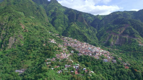 Drone-footage-of-volcanic-mountainside-indigenous-town-Santa-Cruz-La-Laguna,-Guatemala-in-Lake-Atitlan-in-Central-America-highlands-surrounded-by-lush-rainforest-hill