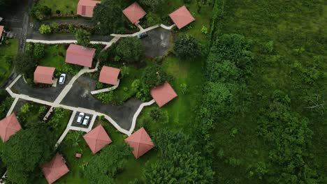 Bird’s-eye-view-Descending-shot,-Scenic-view-of-Red-roof-top-houses-besides-the-La-Tigra-rainforest-in-Costa-Rica