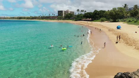 Low-aerial-view-of-kids-playing-at-May's-beach-on-Maui,-Hawaii