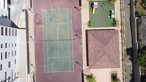 Video-De-Un-Dron-Sobre-Una-Cancha-De-Tenis-En-Una-Zona-Residencial,-Estilo-De-Vida-Deportivo