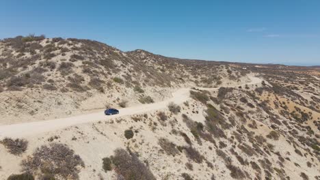 Aerial:-rental-car-driving-on-dirt-track-road-in-desert,-off-grid-exploration