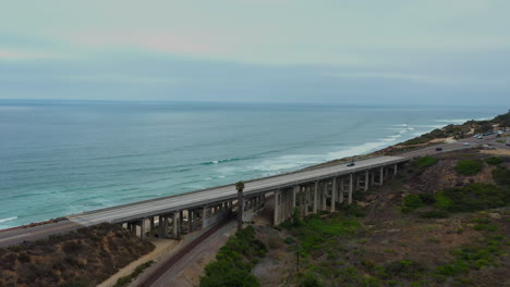 Vehicles-Driving-On-Bridge-Over-Train-Tracks-With-Seascape-In-Del-Mar,-San-Diego,-California,-USA