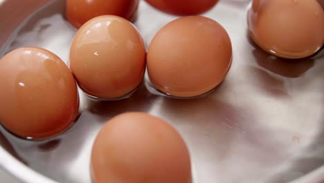 Mano-Selecciona-Huevos-De-Gallina-En-El-Agua-En-El-Plato
