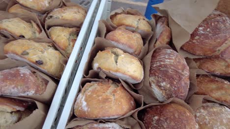 Slow-pan-of-loaves-of-fresh-bread-in-paper-bags-ready-to-be-sold-at-a-local-farmers-market