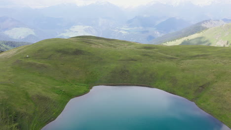Cinematic-rising-drone-shot-of-Oreit-Lake-in-Tusheti-Georgia,-overlooking-the-cliffs-of-the-mountain