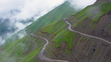 Wide-cinematic-drone-shot-of-vehicle-driving-on-one-of-the-world's-most-dangerous-roads,-the-of-the-Abano-Pass-in-Tusheti-Georgia