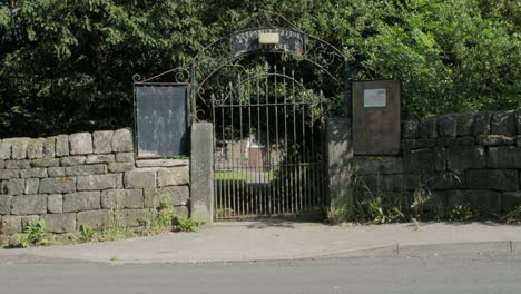 Cemetery-gates-in-high-summer,-gravestones-and-trees-in-Yorkshire,-UK