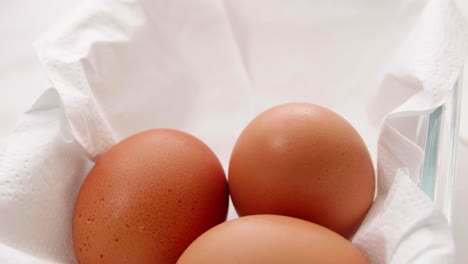 Drei-Frische-Bio-Eier-In-Einem-Rotierenden-Behälter-Auf-Weißem-Verpackungspapier-Für-Die-Zubereitung-Von-Speisen