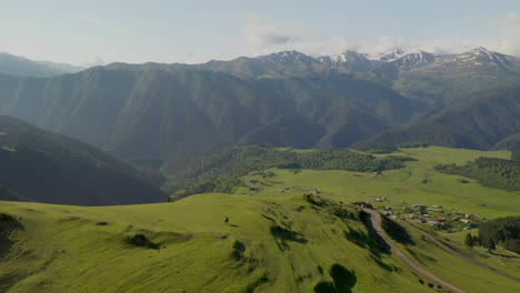 Wide-descending-drone-shot-of-man-riding-a-horse-in-upper-Omalo,-Tusheti-Georgia