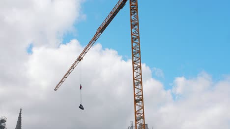 Crane-moving-industrial-load-at-a-construction-site,-blue-sky-in-the-background