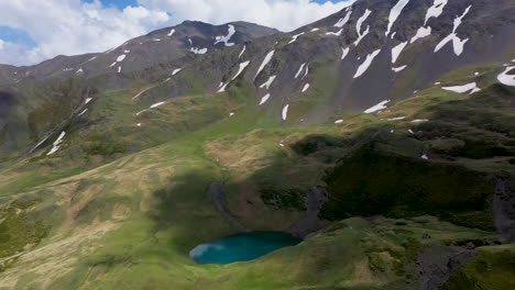 Cinematic-wide-drone-shot-of-Oreit-Lake-in-Tusheti-Georgia,-with-cloud-shadows-moving-across-the-Caucasus-mountains