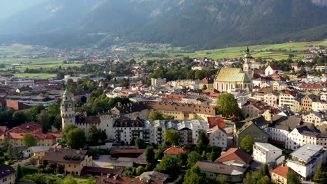 Aerial-view-of-mountain-town-of-Austria-with-churches,colorful-houses,-tower,-autumn-scenery-at-sunset,-river-Austrian-Alps-from-above,-Austria,-Europe
