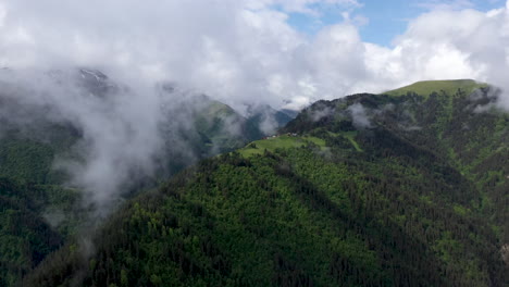 Wide-cinematic-rotating-drone-shot-through-the-clouds-of-a-small-village-on-a-mountain-top-in-Tusheti-Village-in-Georgia