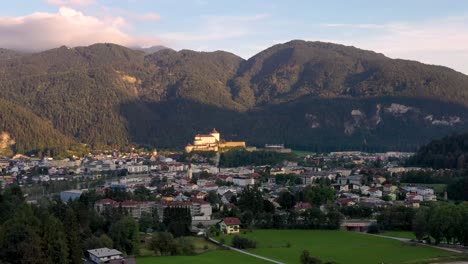 Vista-Aérea-De-La-Ciudad-De-Montaña-Kufstein-Con-Fortaleza-En-La-Cima-De-La-Colina,-Paisaje-De-Verano-Al-Amanecer,-Posada-Del-Río-Serpenteando-Por-El-Valle---Alpes-Austriacos,-Tirol,-Austria,-Europa