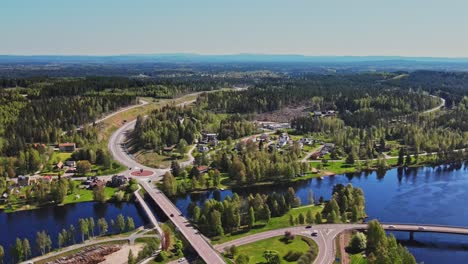 Luftaufnahme-Von-Fahrzeugen,-Die-In-Einer-Straßenbrücke-über-Den-Fluss-Vasterdalalven-Mit-Grünen-Bäumen-In-Vansbro,-Dalarna,-Schweden-Fahren