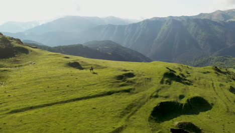 Cinematic-rotating-drone-shot-of-man-horseback-riding-in-the-mountains-of-upper-Omalo,-Tusheti,-Georgia